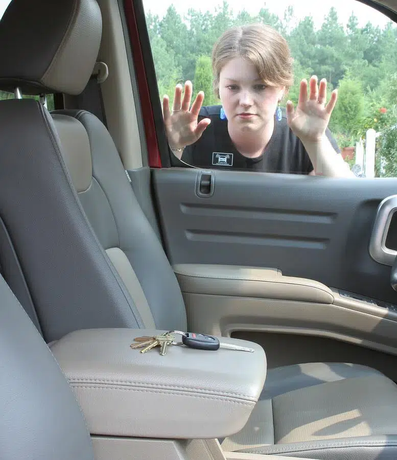 lockout.jpg A person is on the outside of their car looking in through the driver's side window at the keys they locked in the car.