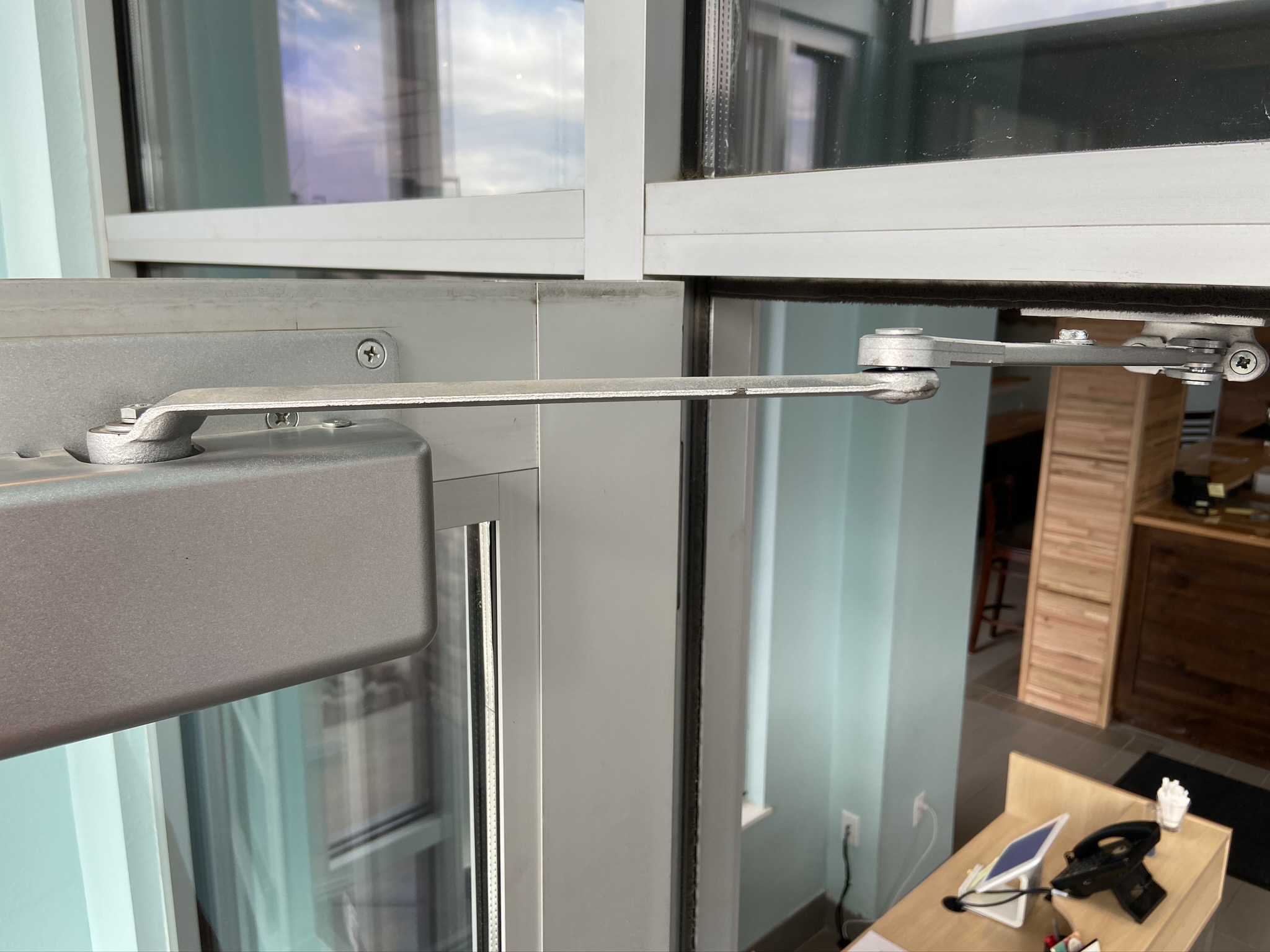 Door closer installed on a commercial door leading into an office building.